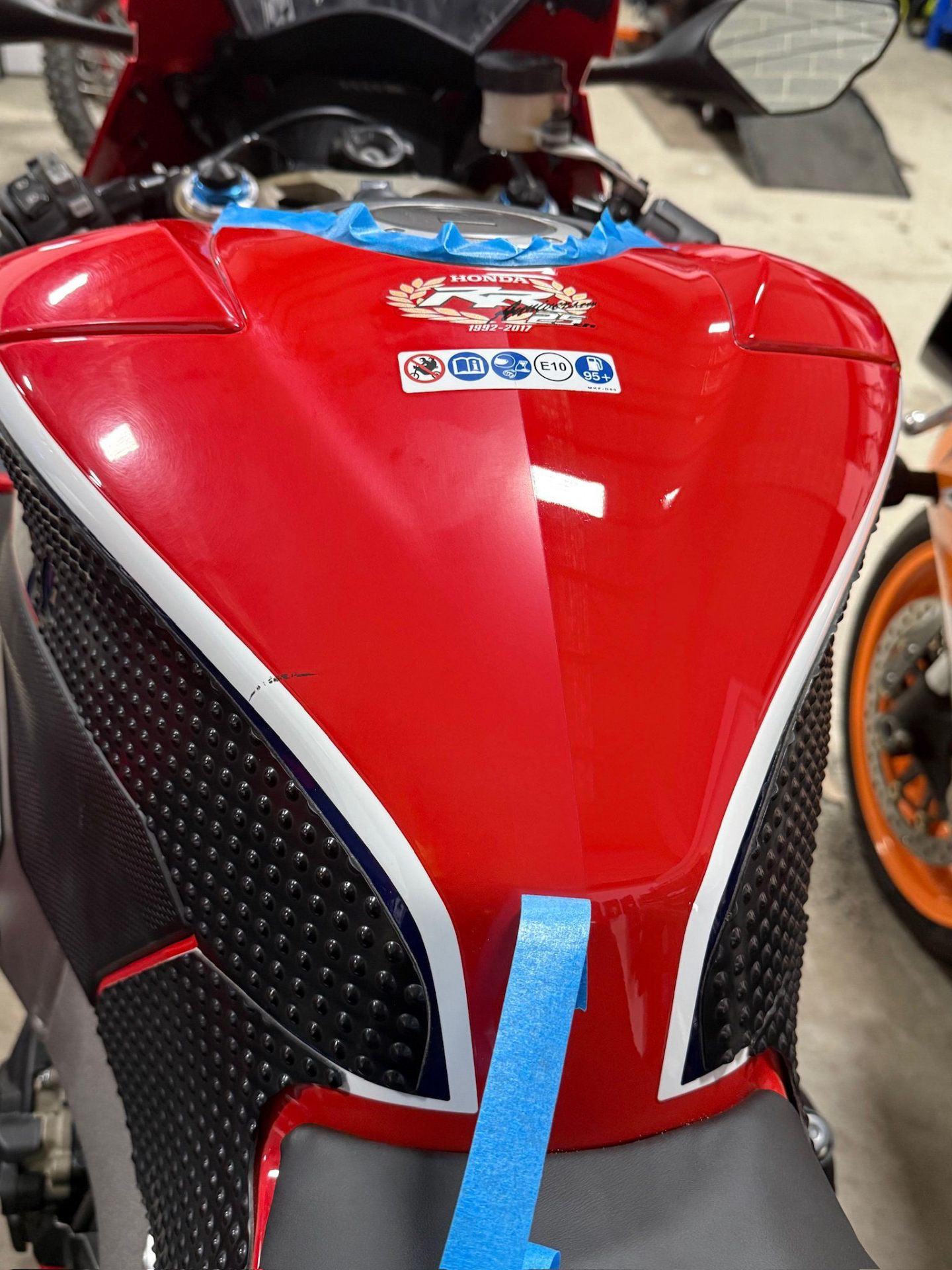 Red Honda motorcycle fuel tank after Stage 3 paint restoration