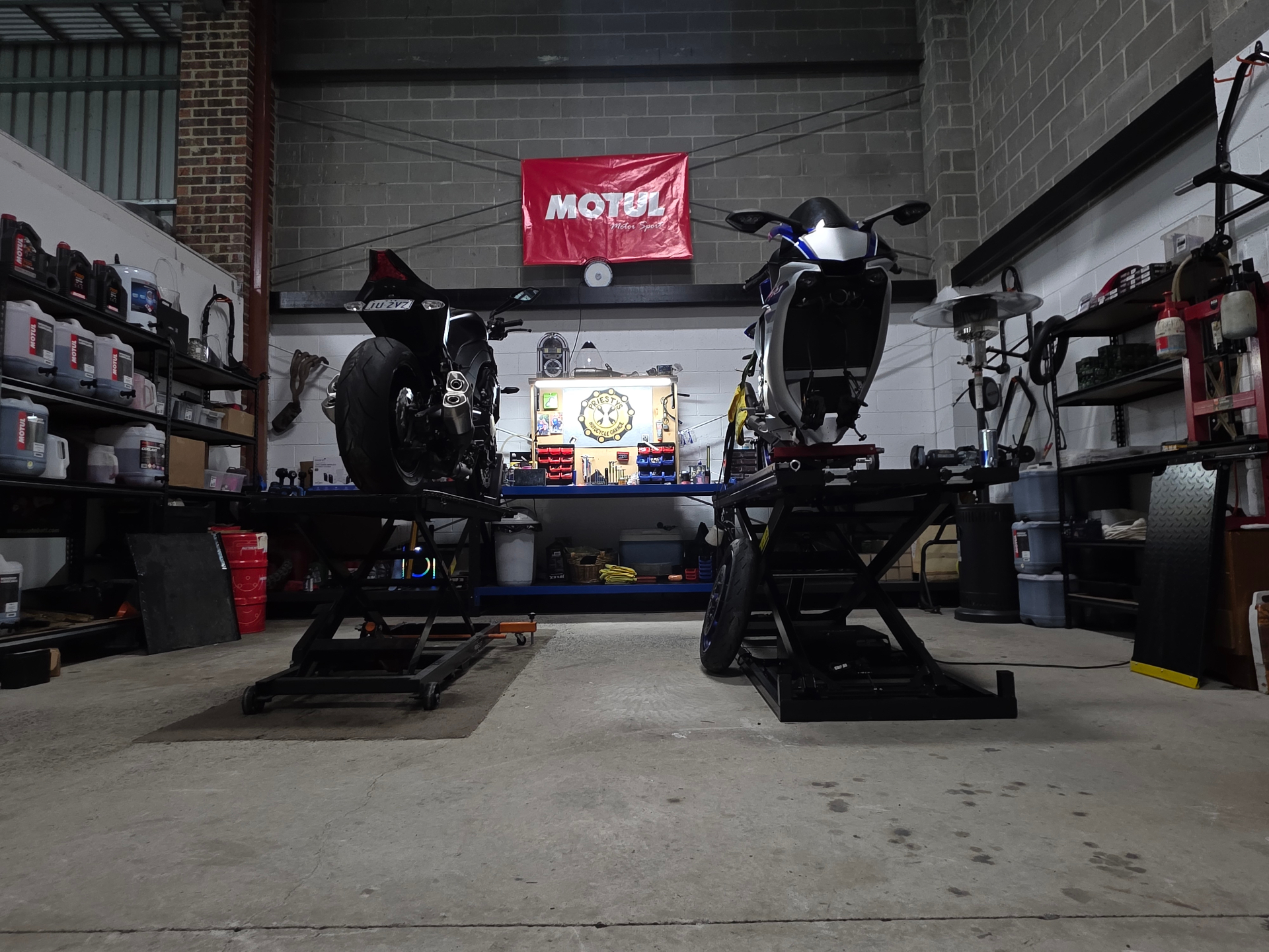 Rear view of two sportbikes on lifts at Priesty's Motorcycle Garage